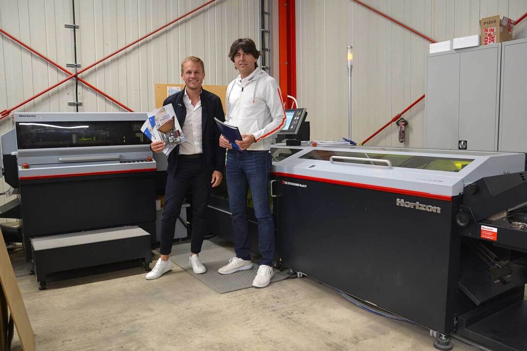 Danny Landsteiner (Key Account Manager, Horizon) und Primus-Print- Geschäftsführer Ralf Rehmet (rechts) am Sammelhefter iCE StitchLiner Mark V.